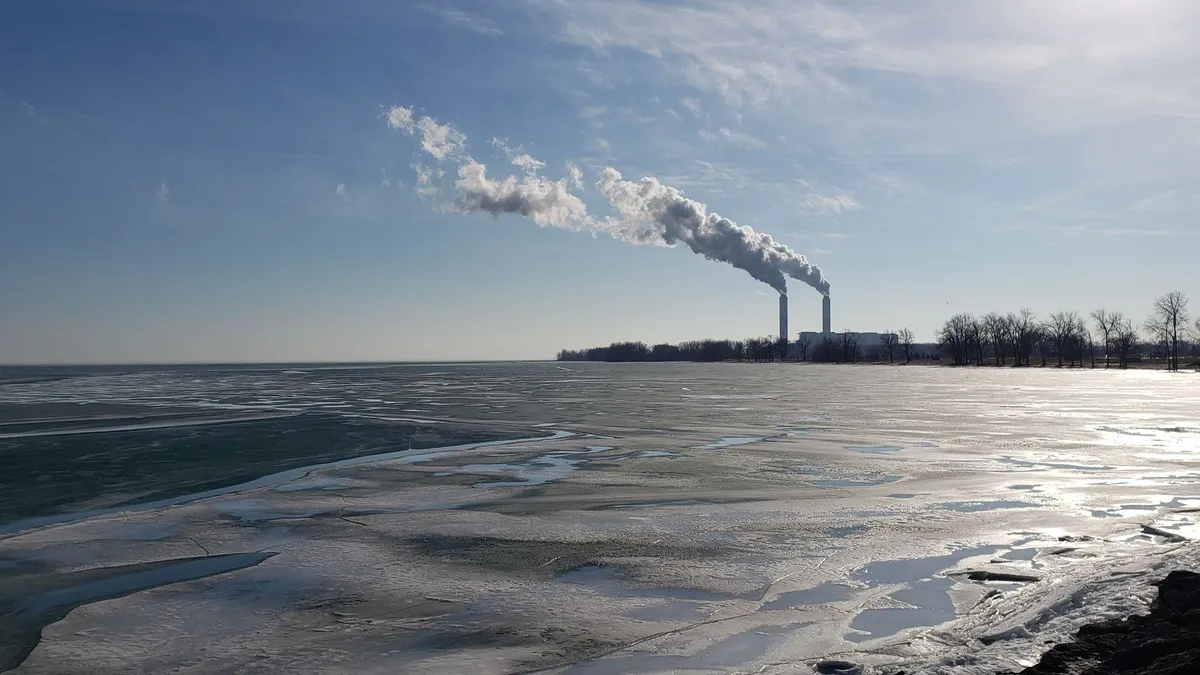 A power plant on the shore of a lake in the winter.