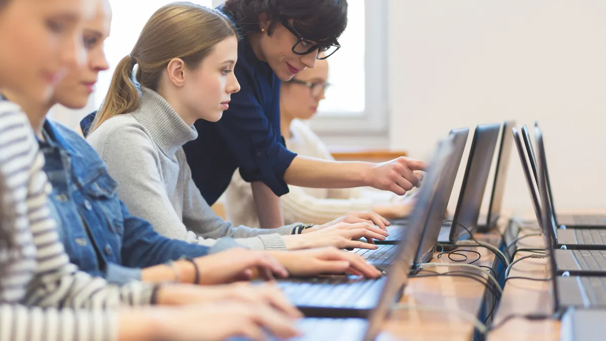 Side view of group of students coding on laptops in a computer lab