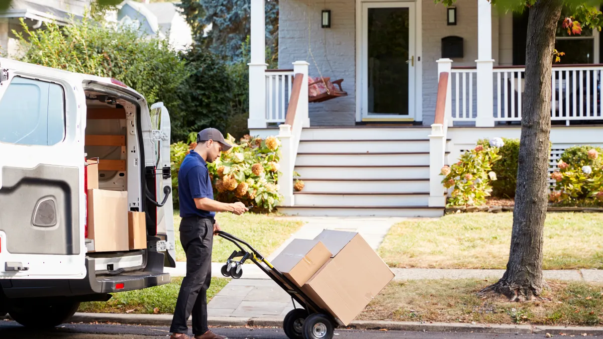 Courier Knocking On Door Of House To Deliver Package.