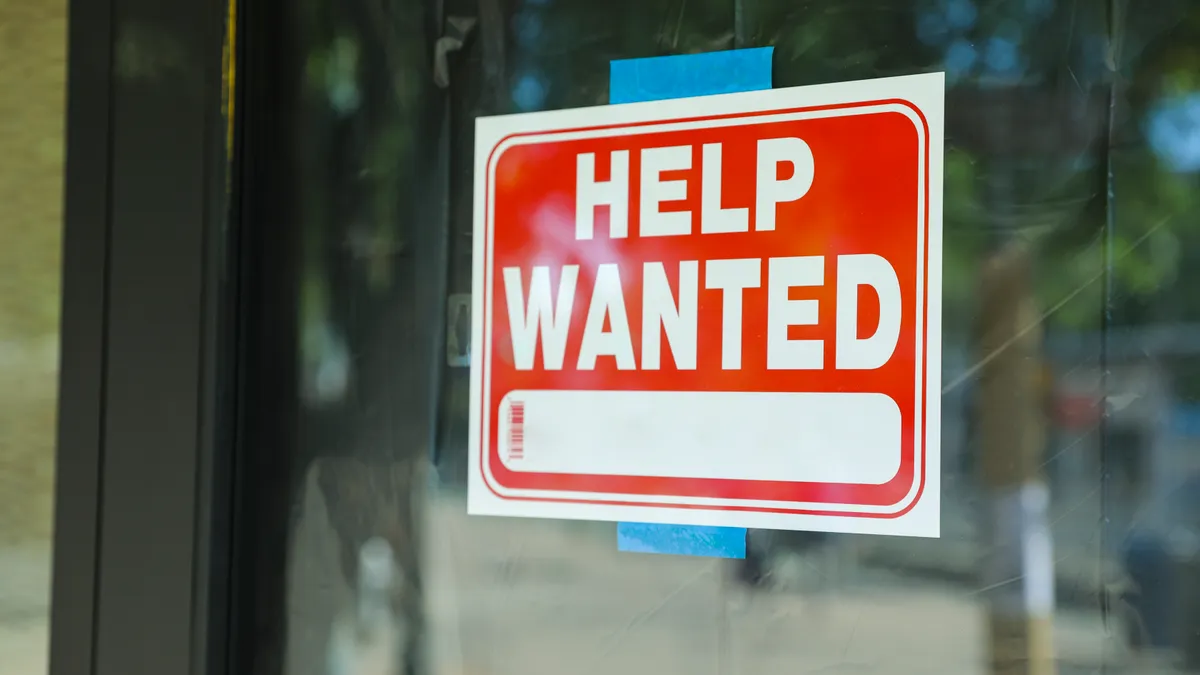 Help wanted sign in front of store front.