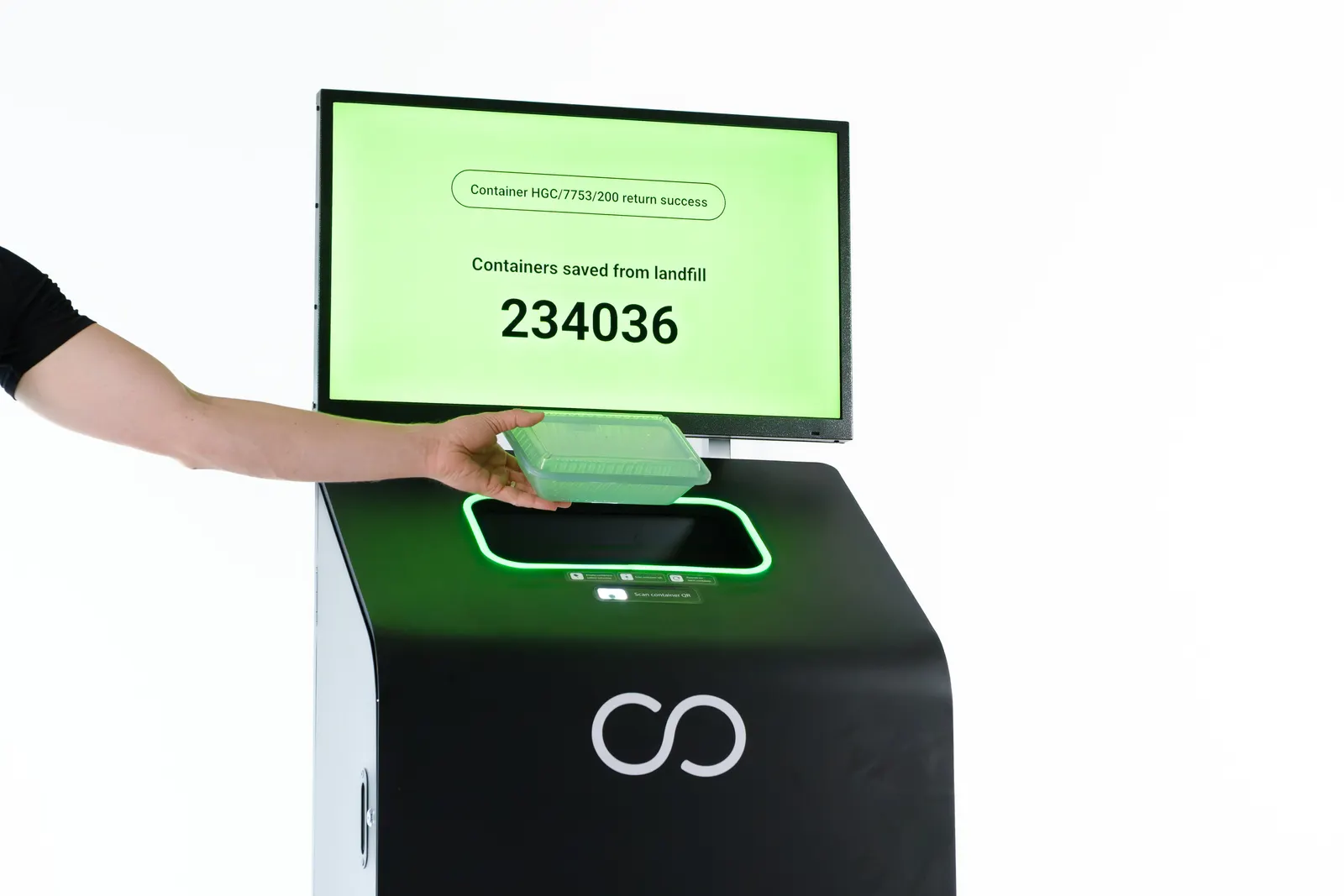 A person's hand is seen putting a container into a collection bin with a digital screen that charts the return.
