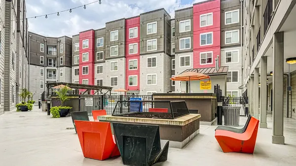 Exterior view of an apartment building, with a deck and chairs in the foreground.