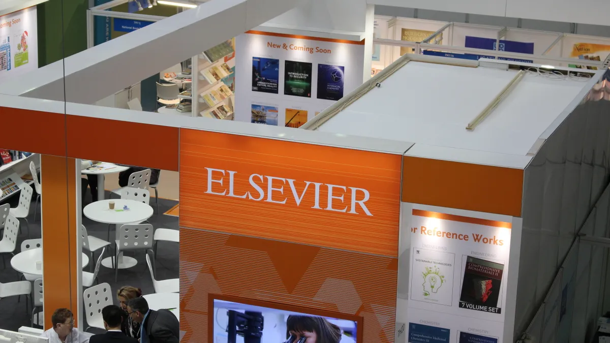 A bird's eye view of an academic convention, focusing on an orange display booth with signage reading "Elsevier."