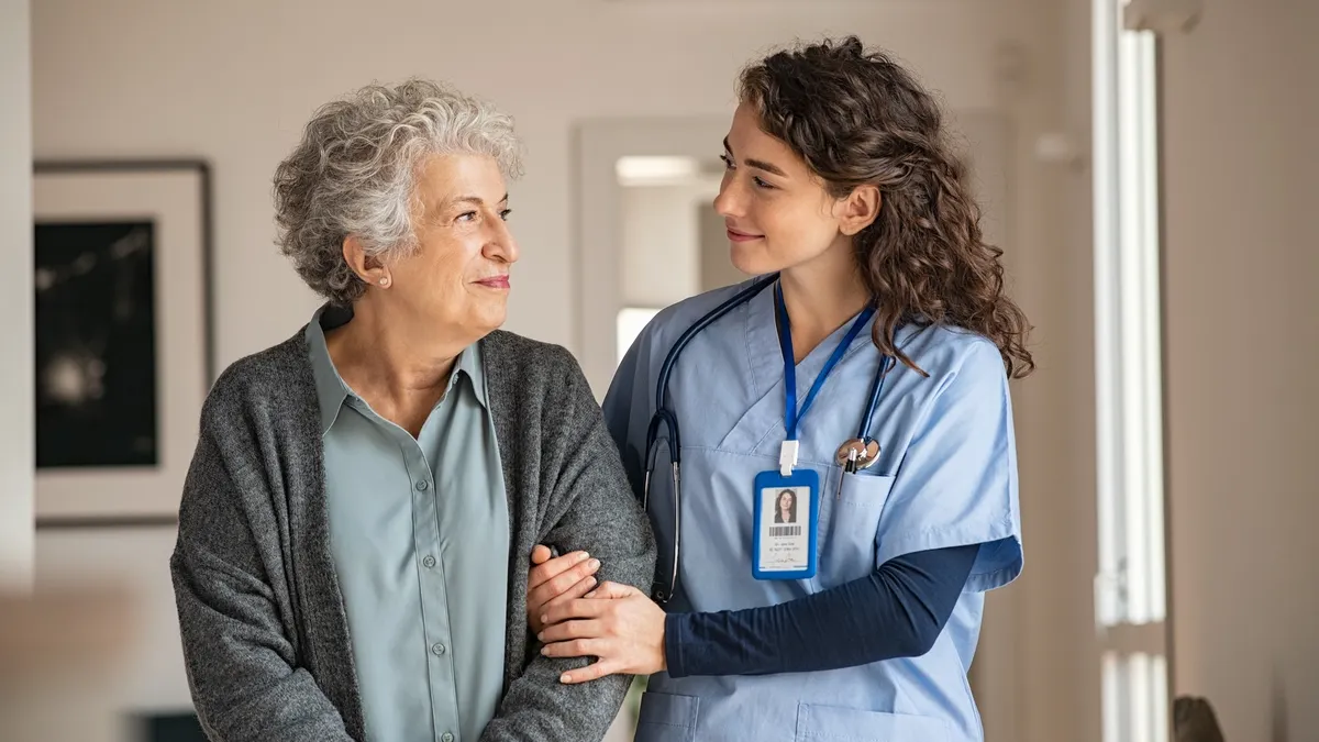 Young caregiver helping senior woman walking.