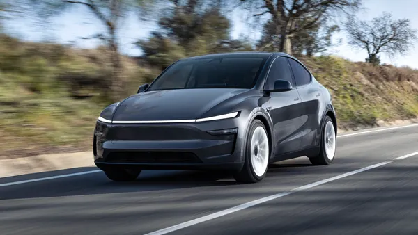 A dark gray 2026 Tesla Model Y driving on a road.
