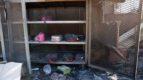 A mental cabinet that has fire damage is open and inside are school lunch boxes.