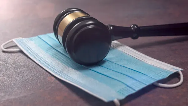 a gavel resting on a blue hospital face mask
