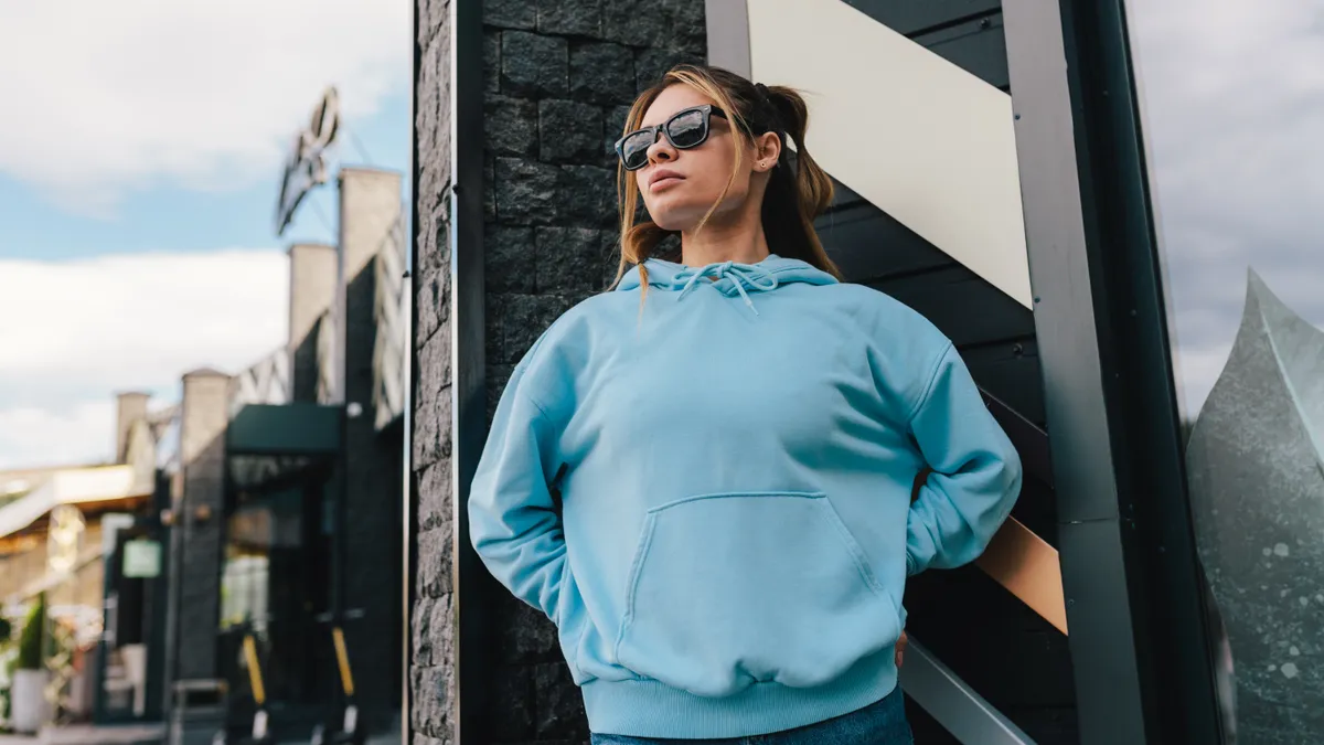 City portrait of young female wearing blue blank hoodie and blue jeans