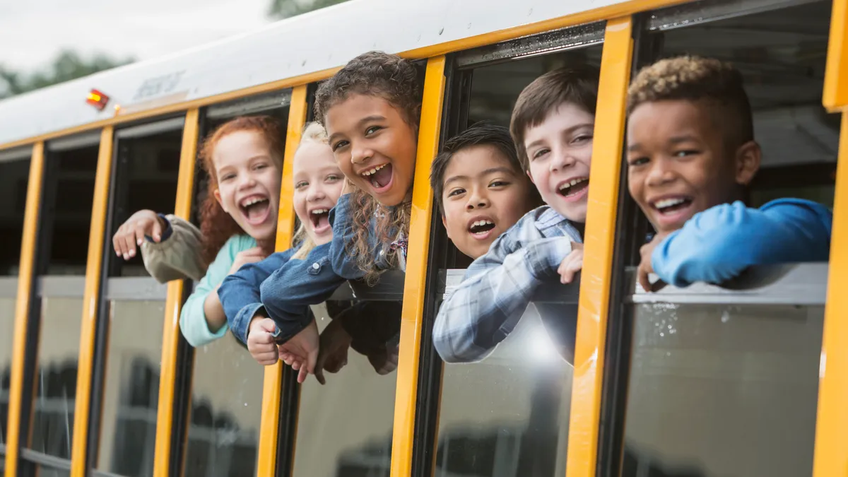 Six elementary-aged children looking out of a bus window