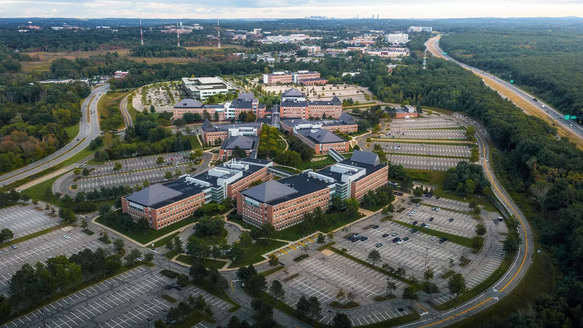 Aerial shot of Blue Sky Center in Burlington Mass., showing about 10 red-brick buildings, about 4 stories each, surrounded by walkways, parking lots, roads and trees