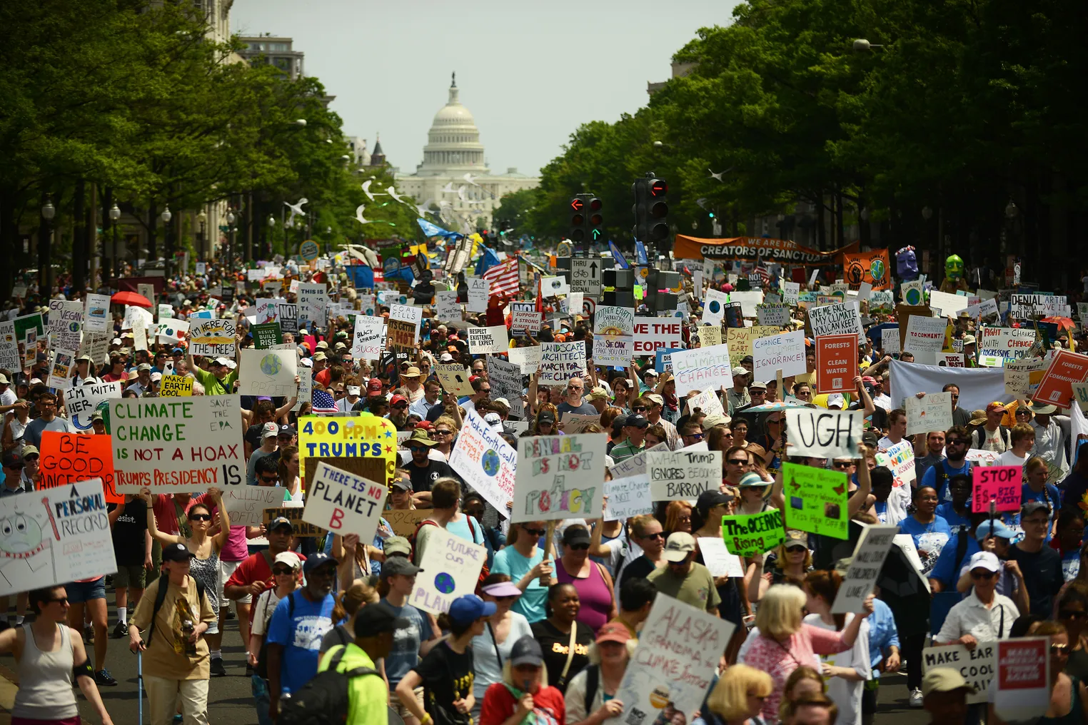 Climate protesters line the street with the Capitol in the background.