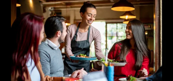 An image of a waitress serving three people at a table.