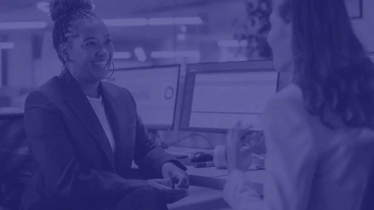 Two Female Colleagues Fondly Talk to Each Other, Laugh and Smile while Working on Computers in Diverse Modern Business Office