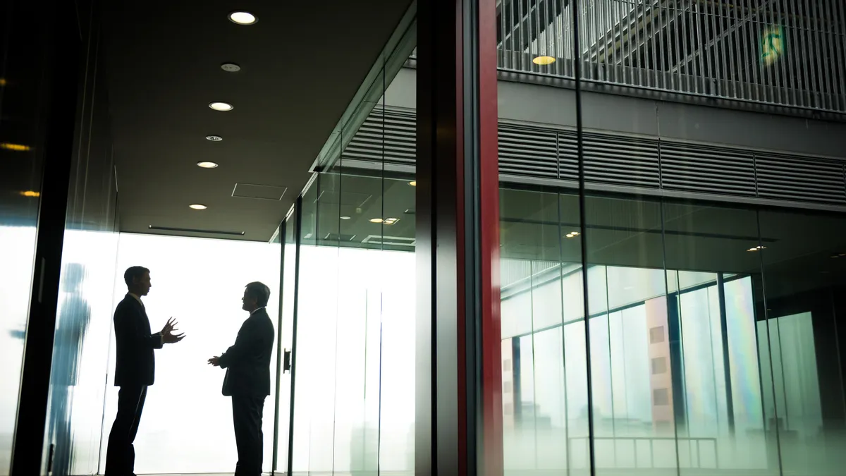 Silhouetted Businessmen discussing in the corridor of a modern office building