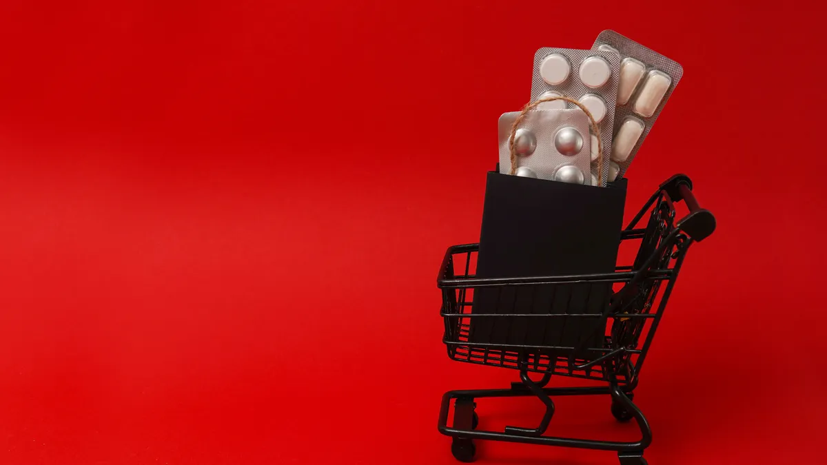 Pills, medical products in black paper bag in shopping cart on red background.