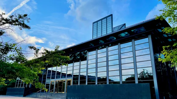A building with lots of glass windows under a blue sky.