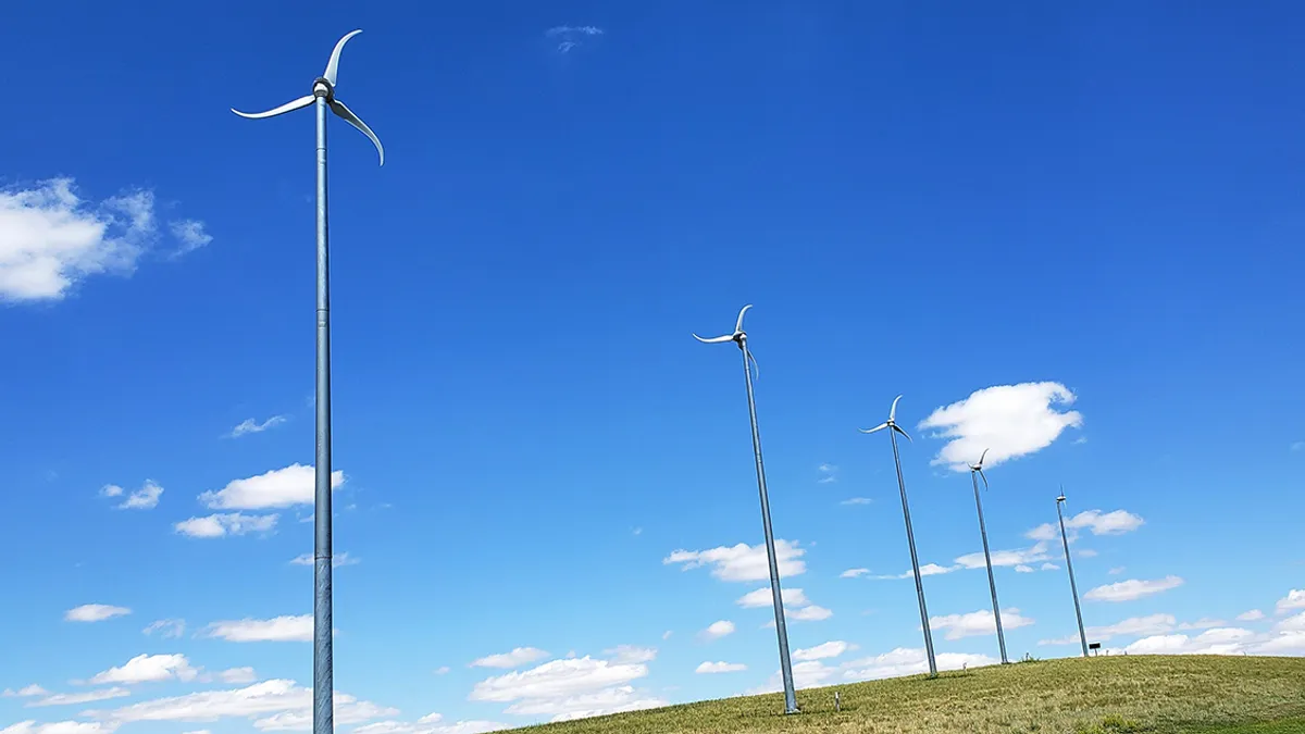 A row of five small wind turbines on a hill.