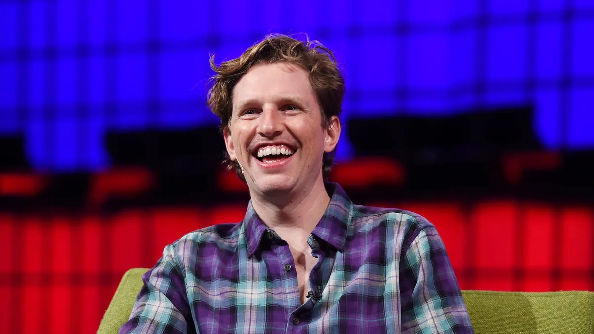 Man smiling on stage at tech event
