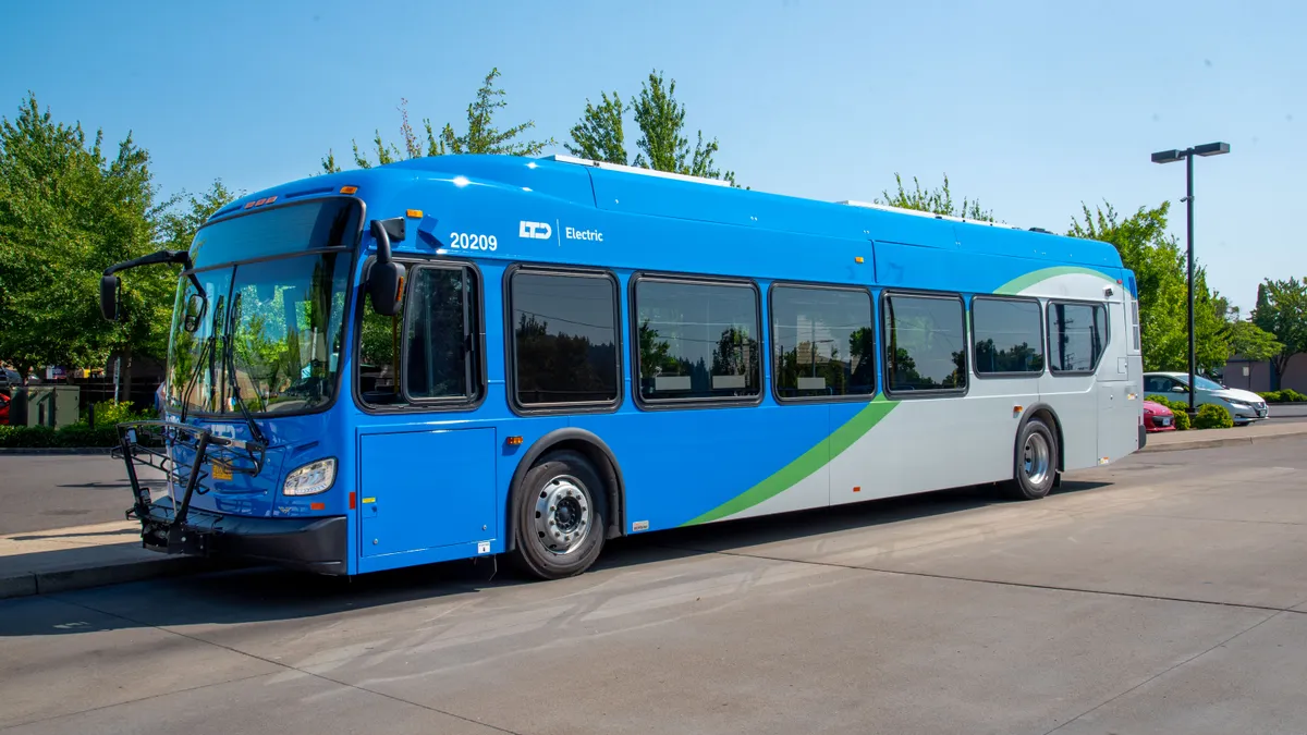 A bright blue electric bus is parked at a curb.