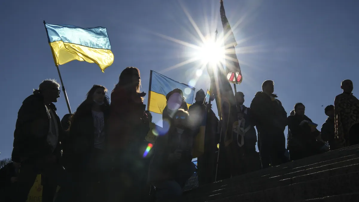 A group of demonstrators hold U.S. and Ukrainian flags as they march in support of Ukraine in its war against Russia.