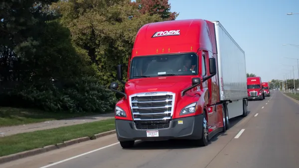 Multiple red Roehl Transport trucks in a single lane on a road.