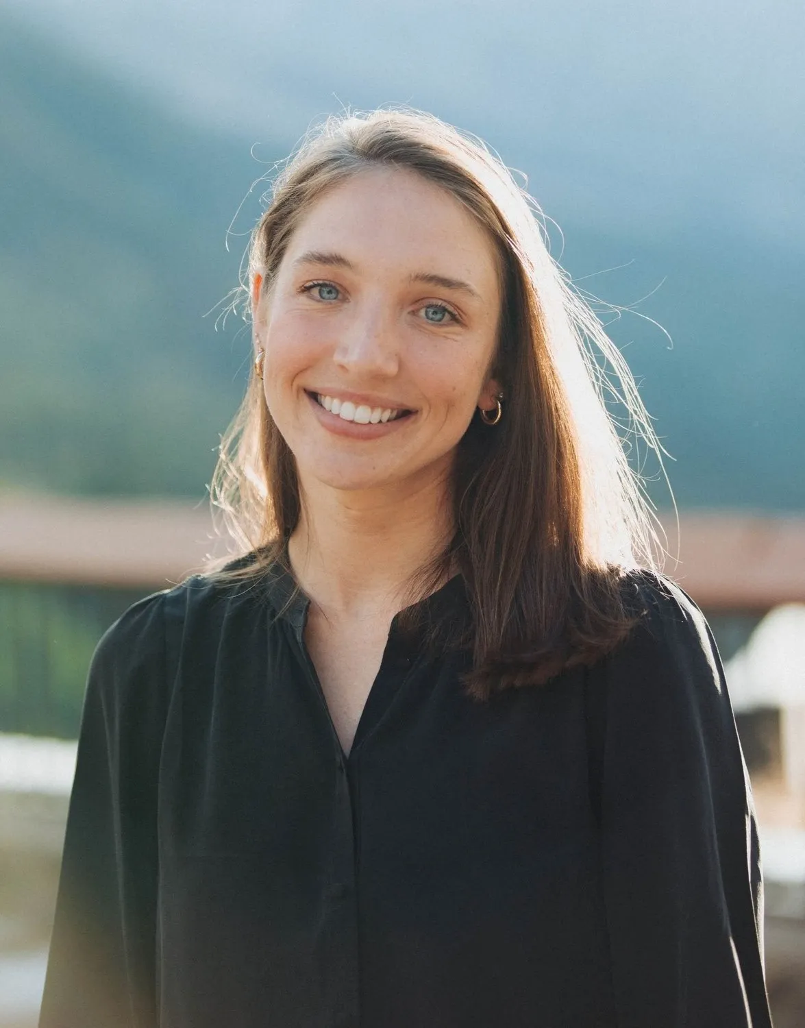 A person wearing a black blouse smiles for a photo.