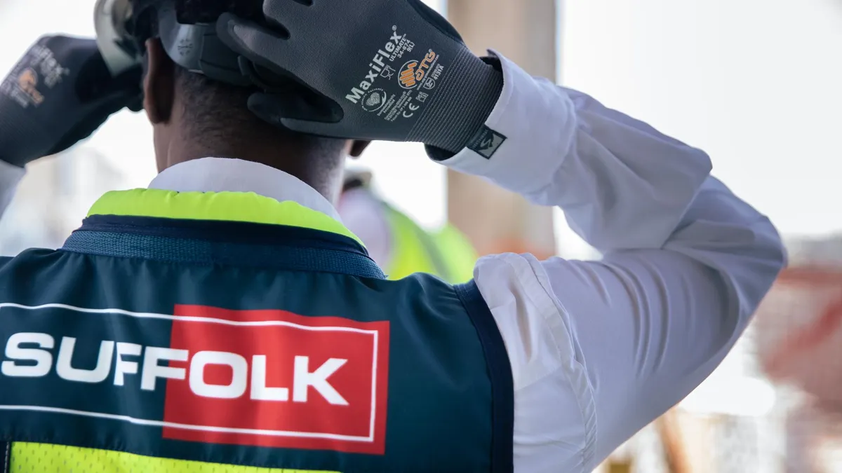 A construction worker dons a hard hat and a Suffolk safety vest.