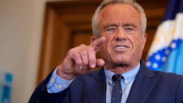 Robert F. Kennedy Jr. in a blue stripe suit points while speaking