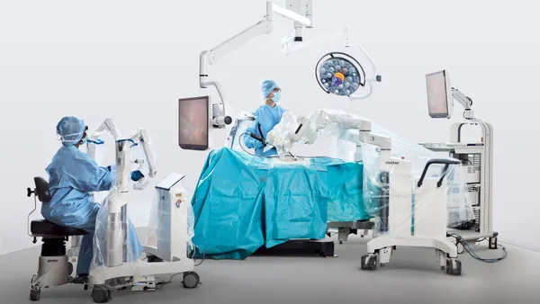 Two clinicians operate Distalmotion's Dexter robotic system in an operating room.