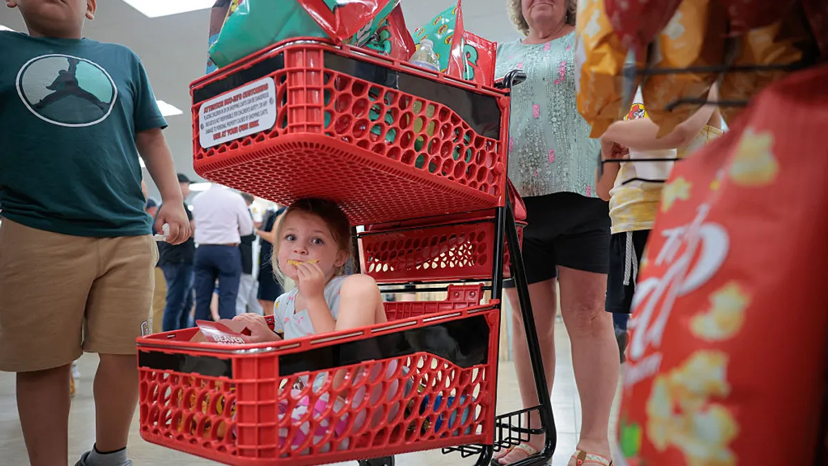 A girl snacks on chips while sitting in a shopping cart