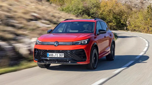 A red 2024 Volkswagen Tiguan SUV driving on a highway.