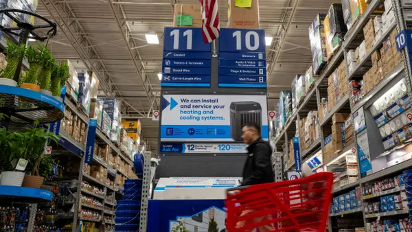 People shop at a home improvement store in front of an ad for a new HVAC system.
