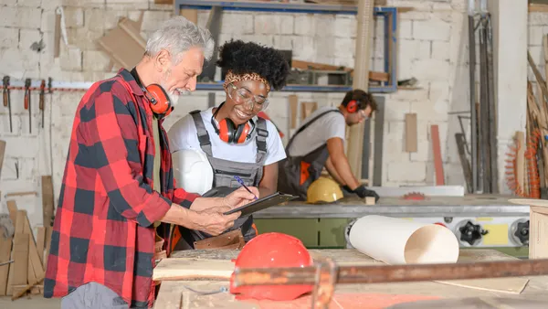 Senior carpenter receives advice from younger worker