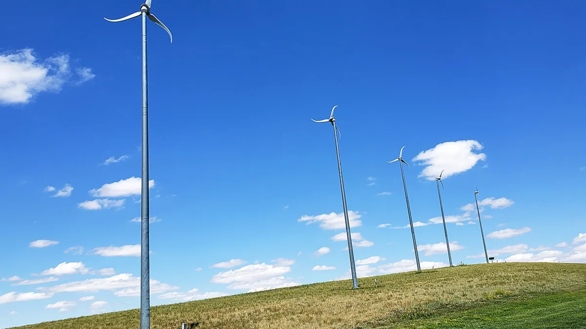 A row of five small wind turbines on a hill.