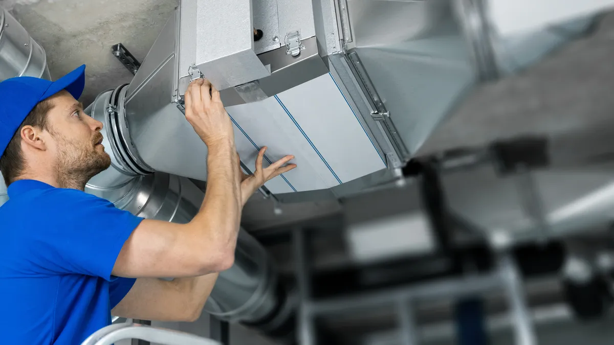 An HVAC technician is at work, repairing a ventilation system.