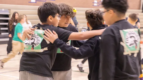Four students huddle together outside a school building.