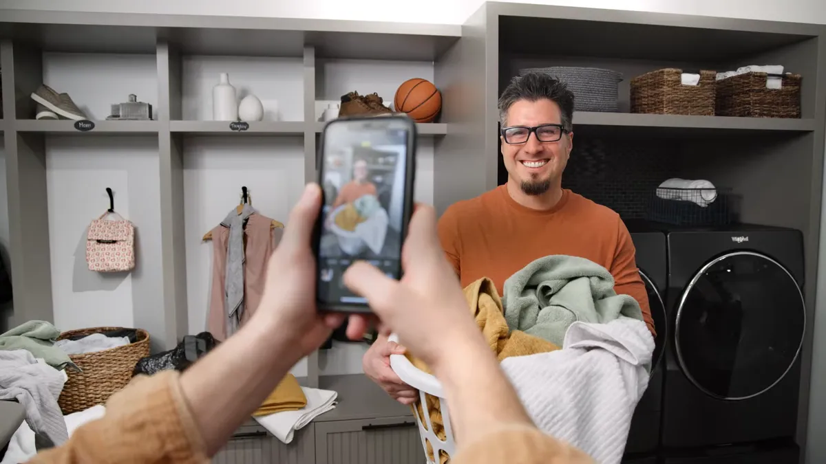 A person takes a photo of a man doing laundry for a new Whirlpool campaign