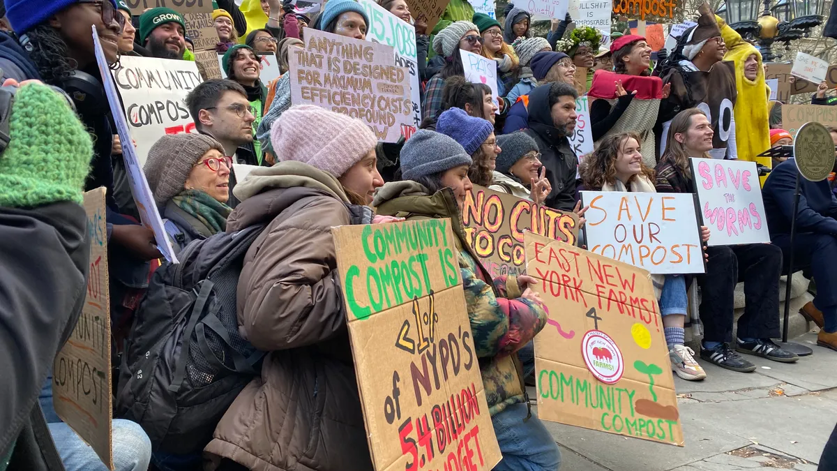 A group of ralliers gather for a photo. Their signs contain messages like "No Cuts to Compost," "Save Our Compost" and "Save the Worms."