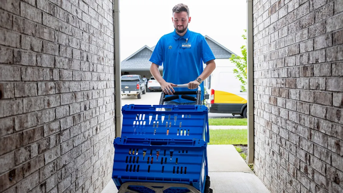 Walmart employee with two crates on a dolly outside of someone's home