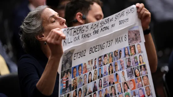 A person holding a sign with the faces of people killed in the  Ethiopian Airlines 737 Max 8 crash.