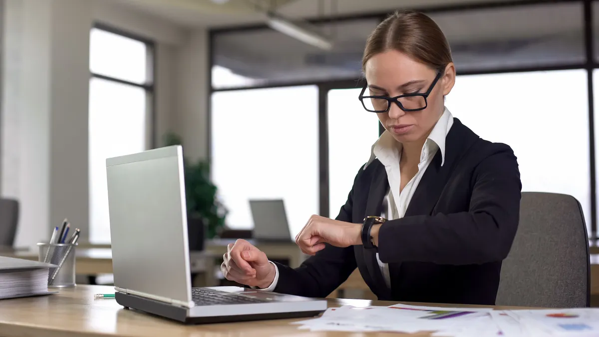 Busy women inside the office looking at her wrist watch