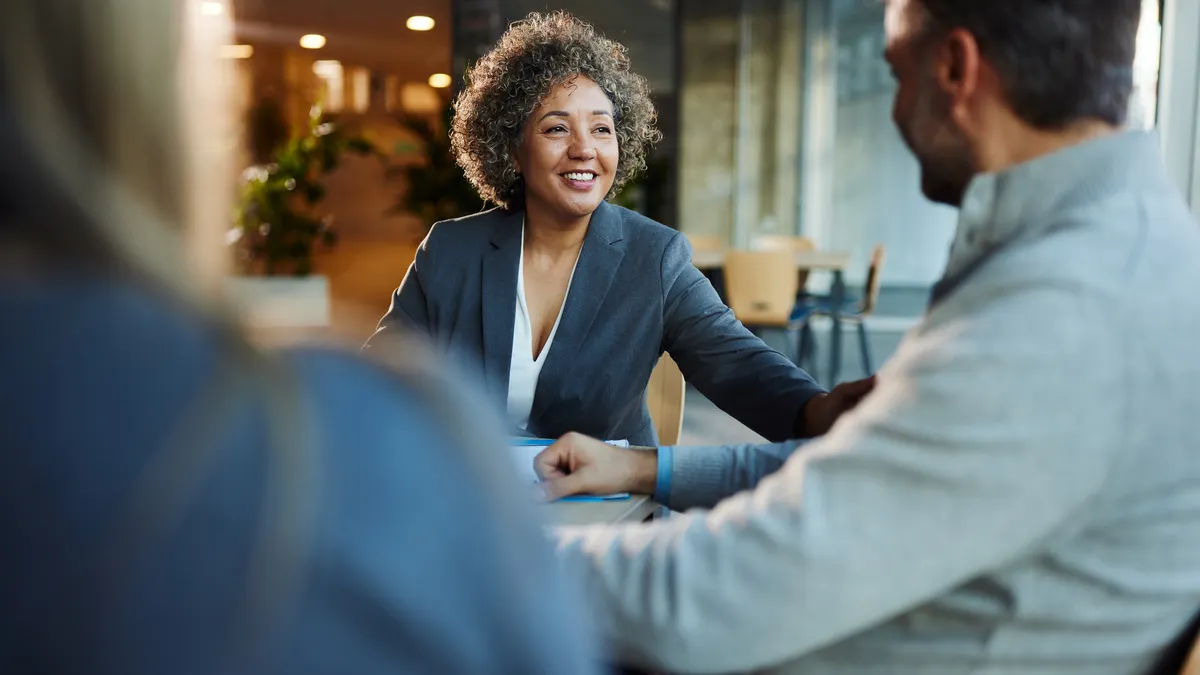 Happy multiracial businesswoman communicating with her colleagues during a meeting in the office.