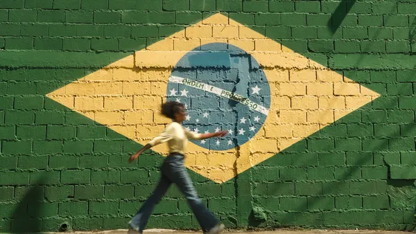 Girl Walking on Street with Brazilian Flag on Wall