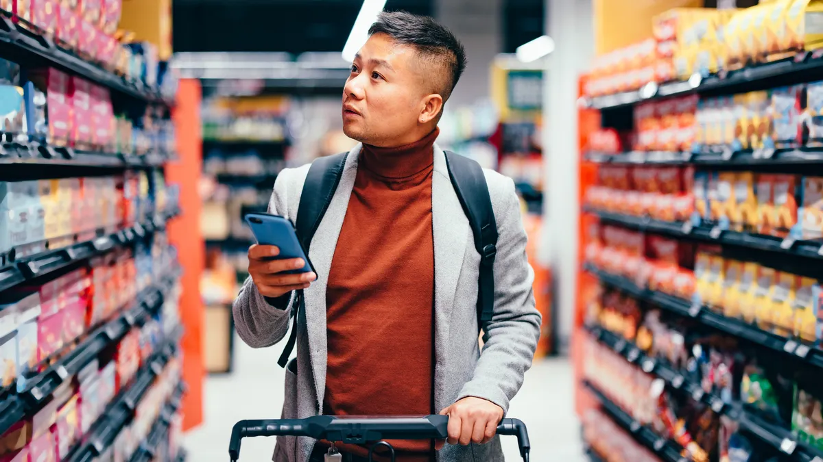 A man checks his phone as he shops