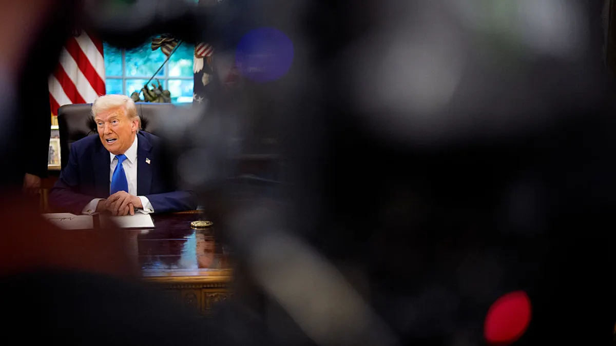 President Donald Trump sitting at his desk in the Oval Office.