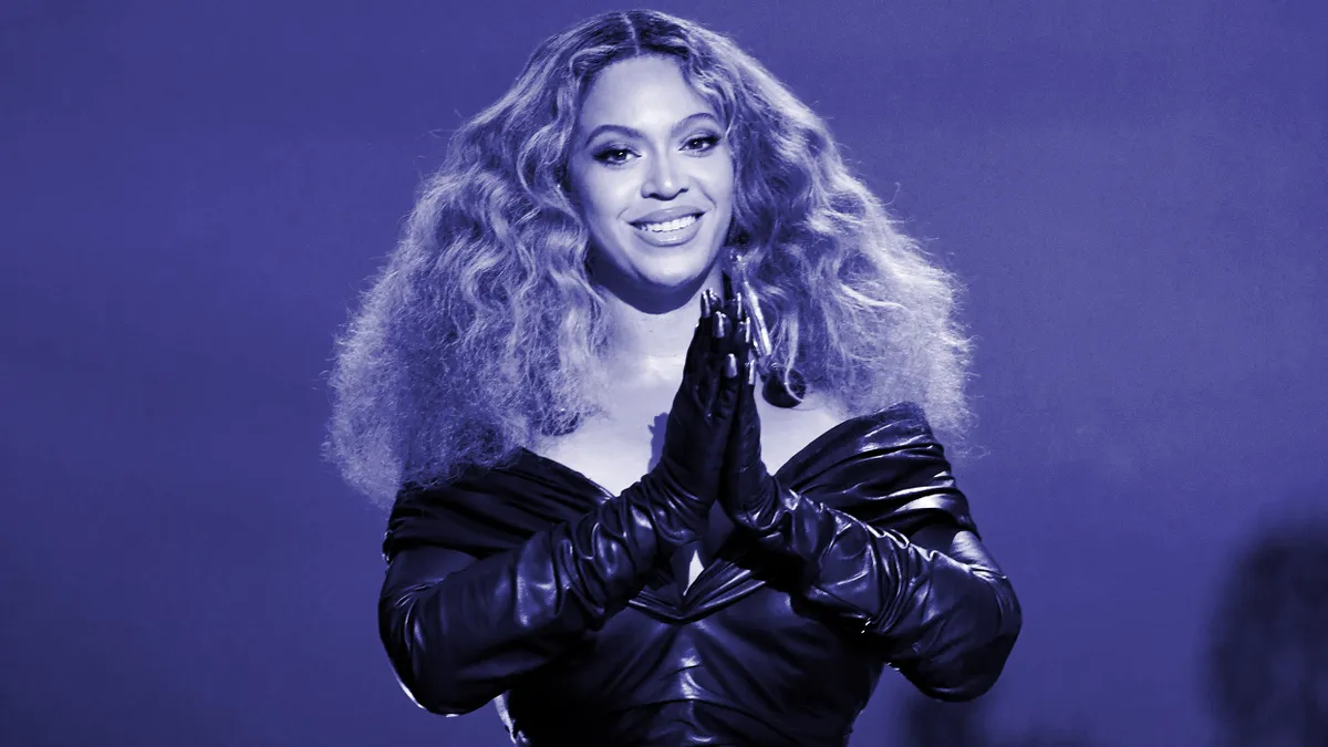 Beyonce smiling at the camera with her hands in a prayer position.