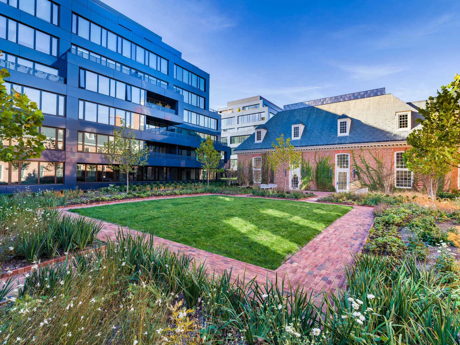 A modern apartment building situated next to a Colonial-style structure.