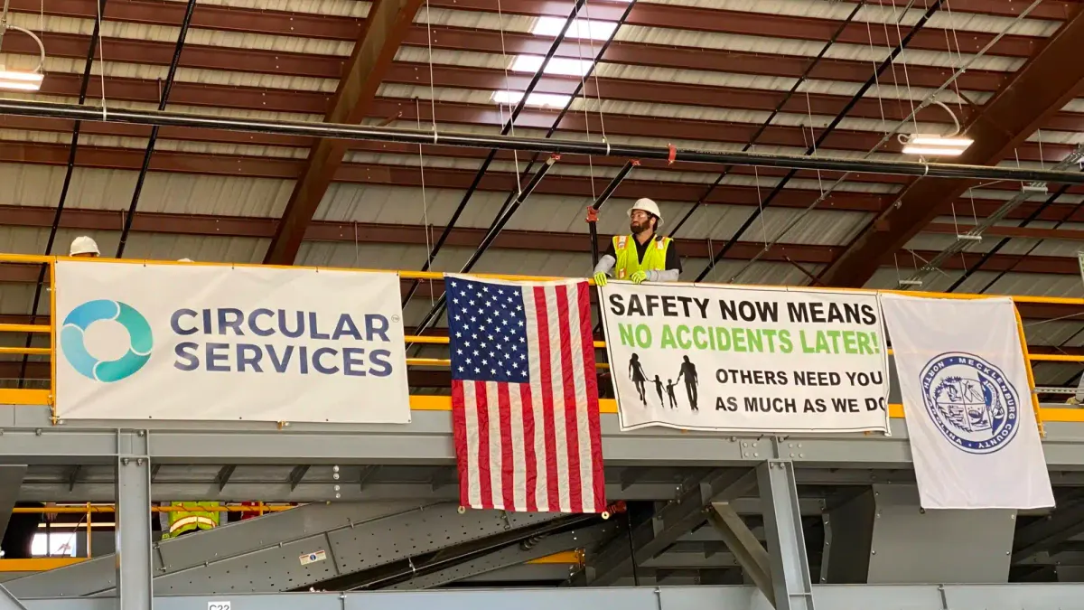 A worker stands near a Circular Materials sign at a MRF