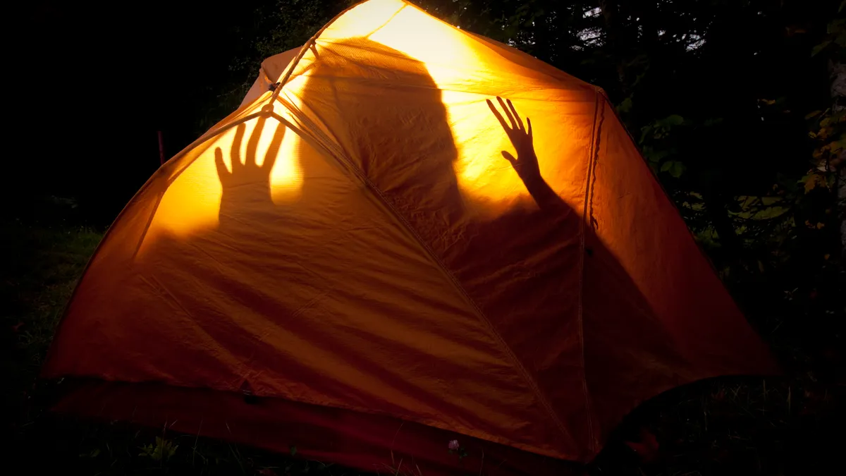 Silhouette of scared child in tent