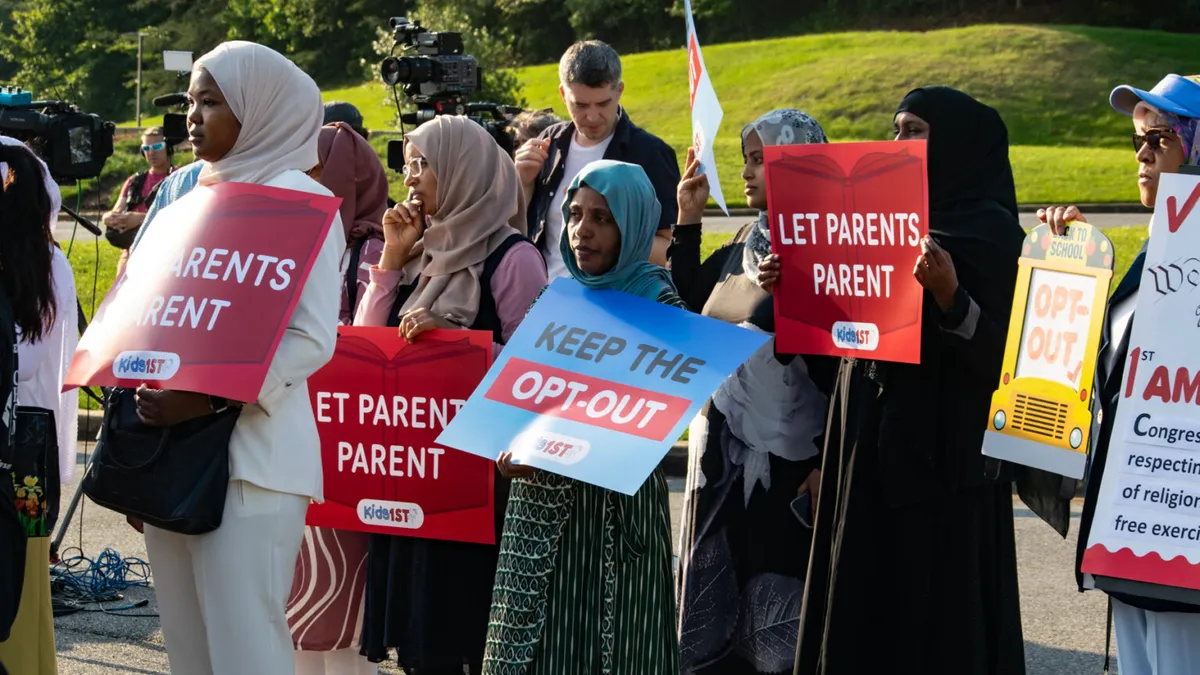 Women wearing hijab hold protest signs